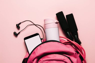 Pembe arka planda spor çantası ve aksesuarlar.