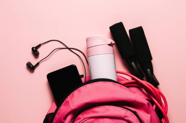 Pembe arka planda spor çantası ve aksesuarlar.