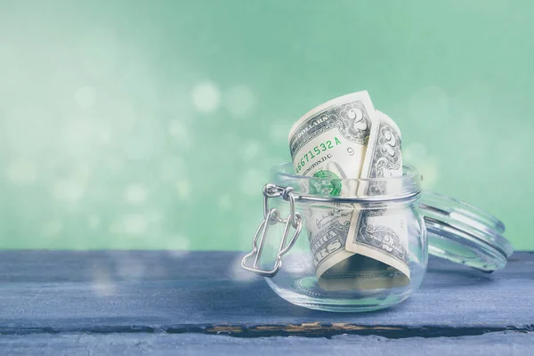 Yeşil arka plandaki kavanoza iki dolar. Tasarruf parası kavramı