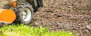 Motosiklet ekicisi arka planda tarlada sürülen yataklara karşı.