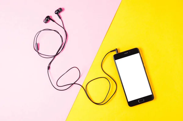 Sarı arka planda akıllı telefon ve kulaklıklar. Müzik uygulaması veya web sitesi şablonu