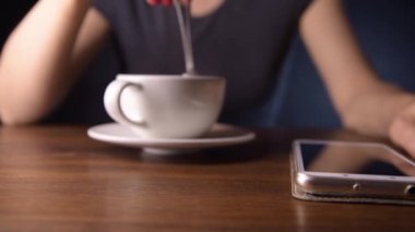 Bir kadın telefon beklerken kadehte içki karıştırır.