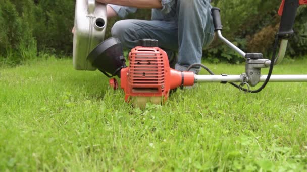 Trädgårdsmästaren fyller gräsklipparen med bensin — Stockvideo