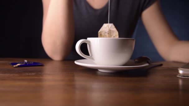 Kobieta parzy herbatę w filiżance czekając na telefon — Wideo stockowe