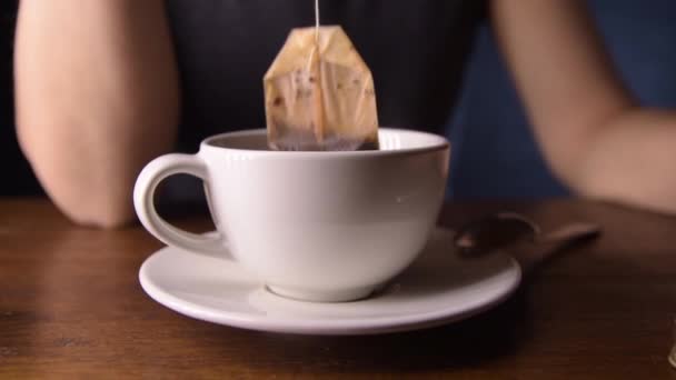 A woman brews a tea bag in a Cup while waiting for a call — Stock Video