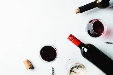 Beyaz bir arka planda kırmızı ve beyaz şarap bardakları ve şişeler. Düz konum ve üst görünüm, metin veya tasarım için boşluk kopyala