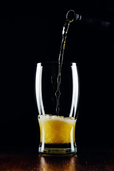 Bira şişeden siyah arka plandaki bardağa dökülür.