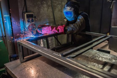 Metal atölyesindeki kaynakçının işi baca ürünlerini demirle üretmek.