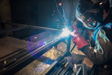 Metal atölyesindeki kaynakçının işi baca ürünlerini demirle üretmek.