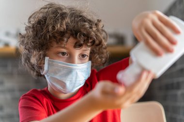 Güvenlik maskeli bir çocuk restoranda eline jel dezenfektanı sürüyor. Covid-19 'un ikinci aşama pandemik konseptinde yeniden açılma.