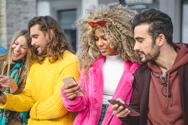 group of people in the city using smartphones and social media applications together. Influencers friends smiling and having fun together.
