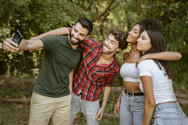Group of interracial best friends having fun in the countryside taking selfie with their smartphones. Generation people using new technologies outdoors. Happiness and friendship concept.