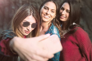 Kızlar sadece selfie çeker. Sokakta akıllı telefonlarıyla fotoğraf çeken genç kadınlar.