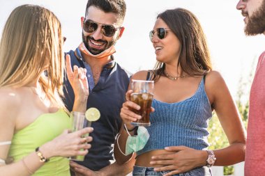 Covid-19 movida: Coronavirus salgınından sonra genç insanlar yüz maskesi takılı halde kokteyller ve buzlu çayla konuşup içiyorlar. Yeni normallik kavramı