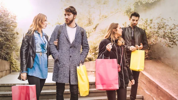 Group of young people walking thru the city holding shopping bags in the autumn season