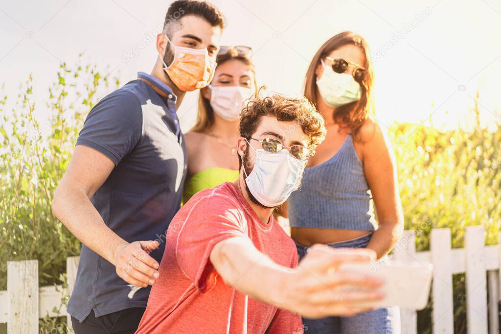 Selfie of young smiling millennials having fun together wearing a protective mask during coronavirus, covid-19, pandemic. New normality life concept