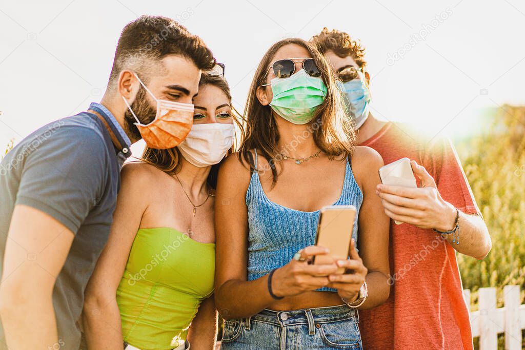 Group of happy friends using smartphone outdoors - People addicted by mobile smart phone in coronavirus time - new normality technology concept with connected men and women - vivid colors