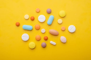 Sarı arka planda bir sürü farklı hap var. 