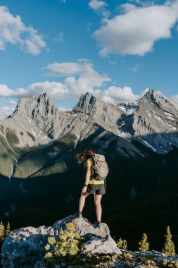 Kanadanın Alberta şehrindeki Grassi Knob dağının zirvesinden Canmore 'un yukarısındaki ikonik üç kız kardeşin güzel dağ manzarasına bakan yürüyüşçü kadın.