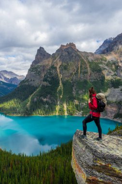 Opabin Prospect 'in tepesinde, O' Hara Gölü ve Mary Gölü 'ne bakan ve arkasında Kanada Kayalıkları olan gezgin kadın. British Columbia, Kanada