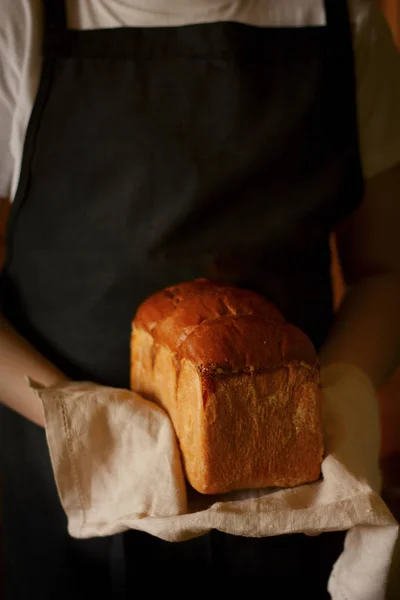 Bochenek świeżego chleba w rękach piekarza — Zdjęcie stockowe