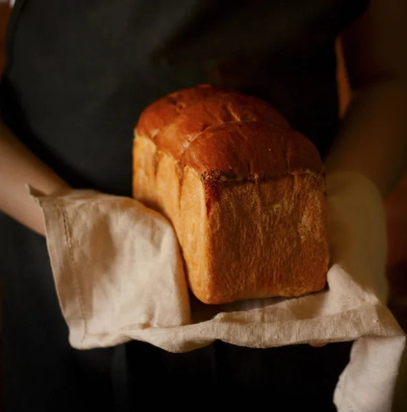Bochenek świeżego chleba w rękach piekarza — Zdjęcie stockowe