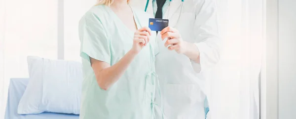 A beautiful girl patient and a young doctor happily carrying a credit card in their hand. Credit card and medical payment for hospital patients. Good health and credit cards for hospital patients.