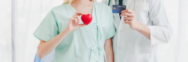 Güzel bir hasta kız ve genç bir doktor ellerinde kredi kartı taşıyorlar. Hastane hastaları için kredi kartı ve tıbbi ödeme. Hastane hastaları için sağlık ve kredi kartları.