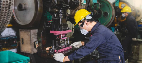 Yüz maskesi ve eldiven takan metal fabrikası işçileri endüstriyel bir tesiste torna ve metal parçaları üretmeye çalışıyorlar..