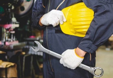 Fabrika mühendisi, hizmet hazırlamak ve endüstriyel alanda çalışmak için üniformalı bir ingiliz anahtarı tutuyor. Fabrikada üniformalı, kasklı, eldivenli ve anahtarlı bir sanayi işçisi..