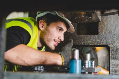 Kafkas erkek bir makine mühendisi fabrikadaki metal işleri için makineyi kontrol ediyor. Bir mühendis kask takıyor ve metal endüstrisinde makine üzerinde çalışıyor..