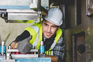 Kafkas erkek bir makine mühendisi fabrikadaki metal işleri için makineyi kontrol ediyor. Bir mühendis kask takıyor ve metal endüstrisinde makine üzerinde çalışıyor..