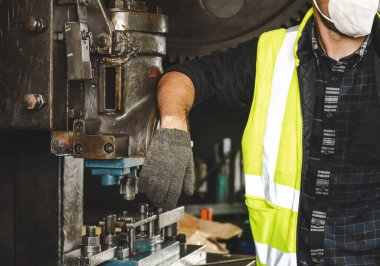 Bir metal mühendisi kolu fabrikadaki mekanik metalin üzerine koyuyor, endüstriyel işçi kavramı..