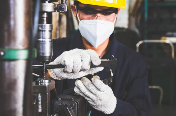 İşçi, metal parçalarının kalitesini ve tasarımını fabrikadaki metal işçiliğinden Vernier Caliper ile kontrol ediyor. Metal parçaları üretimi ve kalite kontrolü.
