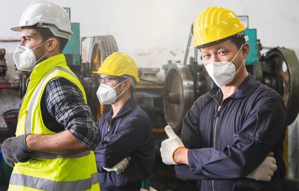 The factory engineer standing and showing thumb up between working inside the factory. Industrial workman working in the factory.