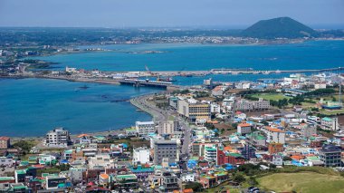 Güney Kore 'nin Jeju adasındaki yüksek bir volkanın eteğinde deniz koyunun her iki tarafına uzanan küçük ve renkli bir şehir.