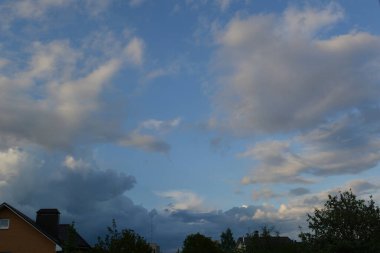 Kıvırcık, kalın bulutlar ve mavi gökyüzündeki bulutlar baharın sonlarında akşam vakti