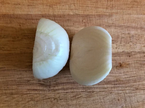 Cebola branca cortada ao meio em uma tábua — Fotografia de Stock