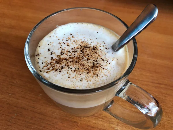 Cappuccino em uma caneca de vidro com espuma branca e canela — Fotografia de Stock