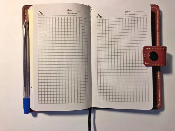 Penna blu con un quaderno marrone su sfondo bianco — Foto Stock