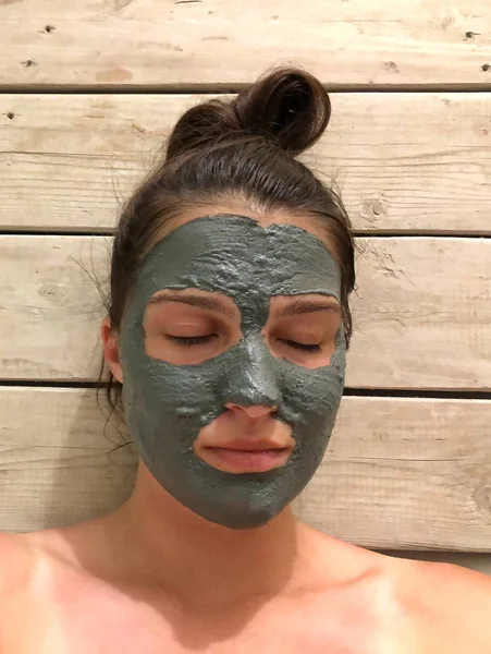 Beautiful woman with a clay or a mud mask on her face