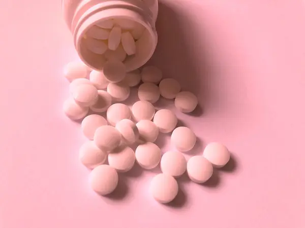 Pastillas sobre fondo rosa. Atención médica y tratamiento — Foto de Stock