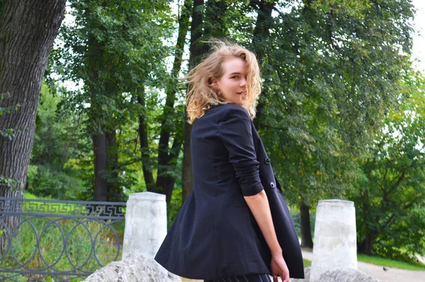 A sexy young woman in a business black suit is stands — Stock Photo, Image