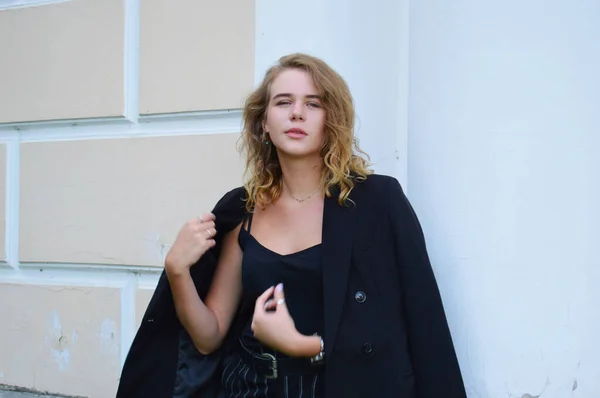Bir iş siyah takım elbise seksi bir genç kadın duruyor — Stok fotoğraf