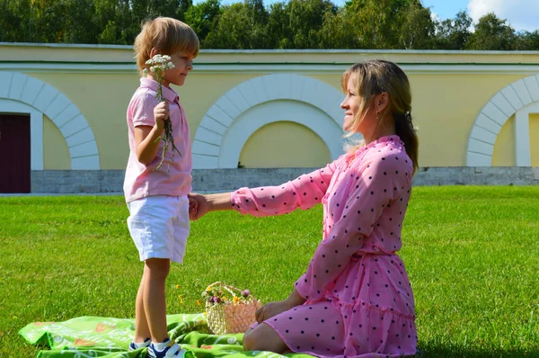 Niñito en la hierba con su madre en el parque de verano . — Foto de Stock