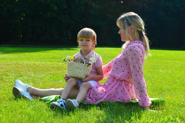 Niñito en la hierba con su madre en el parque de verano . — Foto de Stock