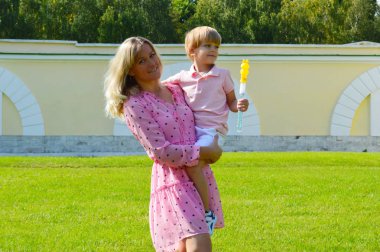 Küçük çocuk annesiyle birlikte yaz parkında çimlerin üzerinde..