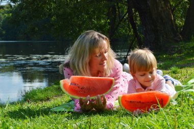 Nehir kıyısında annesiyle birlikte karpuz yiyen küçük bir çocuk..