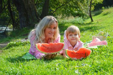 Nehir kıyısında annesiyle birlikte karpuz yiyen küçük bir çocuk..