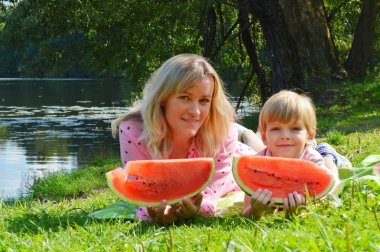 Nehir kıyısında annesiyle birlikte karpuz yiyen küçük bir çocuk..
